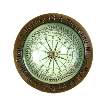 An overhead shot of the brass compass, engraved around the edge with the words: A journey of a thousand miles begins with a single step.