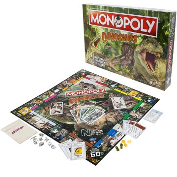 The front of the Monopoly Dinosaurs packaging is displayed with the board game set out ready to play. The packaging has dinosaur illustrations on it in a jungle setting.