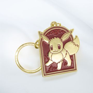 The burgundy key ring tag depicts the Pokémon Eevee in gold. The chain and ring are gold.