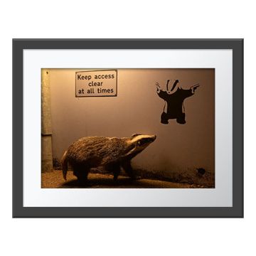 No Access Wall Print in a dark grey frame with a white border. The print is of a badger walking past a wall with the sign 'Keep access clear at all times'. The badger looks up at a graffiti drawing of a badger.