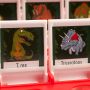 A close up of the T. rex and Triceratops dinosaur illustrations on one of the boards (with the red tray).