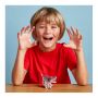 A young boy with blond hair and a red t-shirt holds his hands up as if they were claws. The completed model is below him on the table.