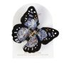 The butterfly hair claw displayed on its packaging. The black and blue wings have white and gold spots.
