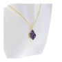 The necklace is displayed on the chest of a white bust. The pendant is purple and the chain is gold.