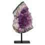 The amethyst is triangular in shape and displayed on a pole fixed to a stand. The amethyst’s purple middle is surrounded by a pale purple, almost white layer of crystal, encased in a dark edge. 