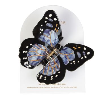 The butterfly hair claw displayed on its packaging. The black and blue wings have white and gold spots.