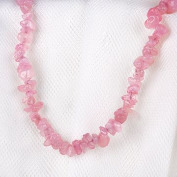 A close up of the Rose Quartz Chip Necklace displayed on a white cloth background. Each bead is a different shape and a different shade of pink.