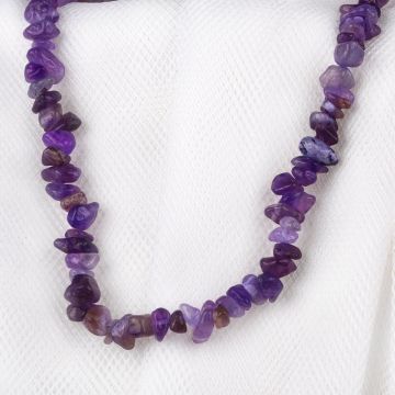 A close up of the Amethyst Chip Necklace, displayed on a white cloth background. Each bead is a different shape and a different shade of purple.