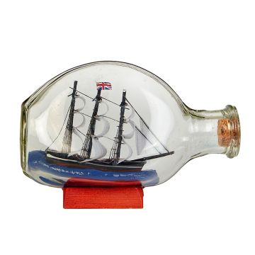 The corked see-through bottle is shown side-on, resting on an orange stand. Inside is a black ship with a Union flag and white sails on its masts. The ship is on a blue base.