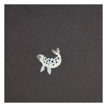 A close up of the embroidered seal with its tail curved up. It is similar to a Weddell seal in features, with a grey body and black spots