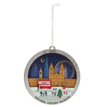 The round, wooden decoration depicts famous landmarks in London at night, including the Natural History Museum, and hangs on a white ribbon.