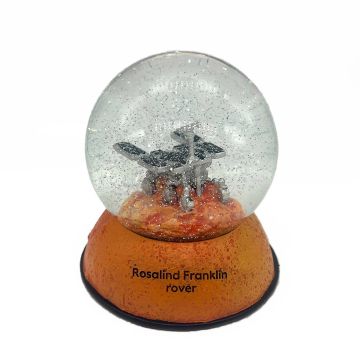The glittery glass globe has a model of the rover inside it. It rests on the round base, designed to look like the scarred orange surface of Mars. The words 'Rosalind Franklin rover' are printed in black on the base.