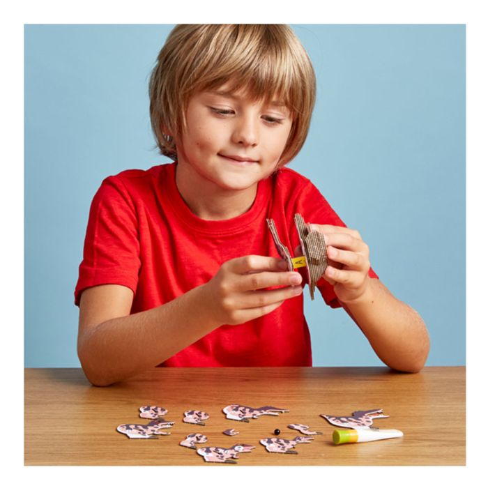 A young boy with blond hair and a red t-shirt is fixing the Spino model pieces together.