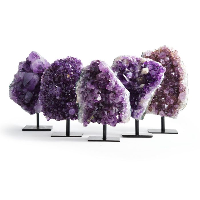 A group shot of five amethysts each mounted on a stand. Each one of the five is shaped differently and a different shade of purple.
