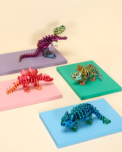 Each of the four brightly coloured dinosaur skeleton fidget models stand on a display board against a yellow background. Clockwise from top are: T. rex, Triceratops, Ankylosaurus and Stegosaurus.