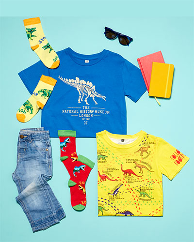 Dinosaur-themed socks and two kids’ t-shirts laid out on a blue background.