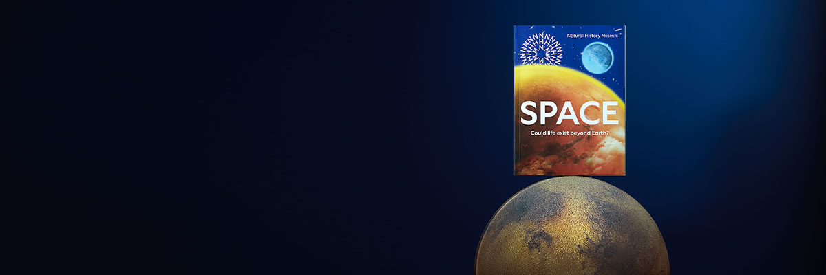 The space exhibition book balances on top of a Mars-like planet, against a dark background. The front cover features a Jupiter-like planet with ‘Space’ in capital letters and the words ‘Could Life Exist Beyond Earth?’ in smaller font underneath.